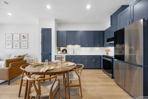 a kitchen with a refrigerator a stove a sink a dining table and chairs