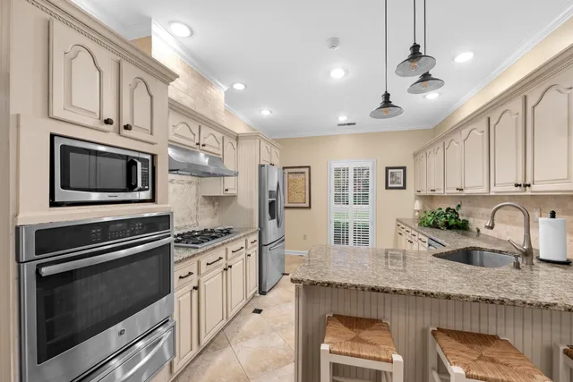 a kitchen that has stainless steel appliances granite countertop a stove and a sink