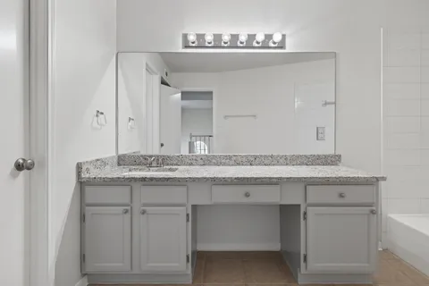 a bathroom with a granite countertop sink and a mirror