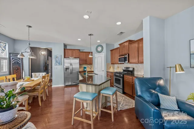 a living room with furniture a dining table chairs kitchen view and a chandelier