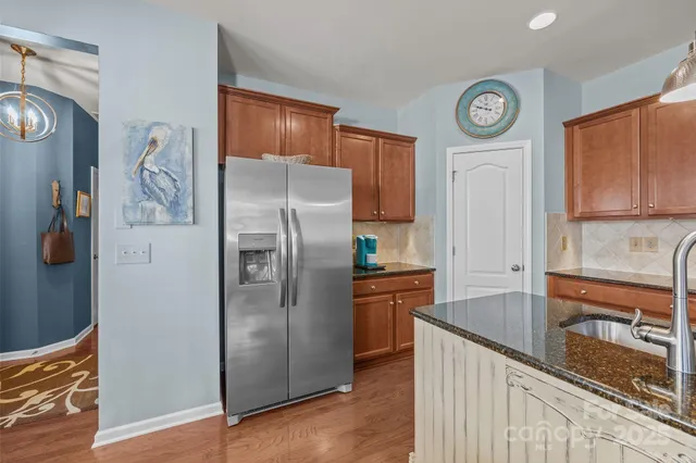 a kitchen with stainless steel appliances granite countertop a refrigerator a stove and a sink with wooden floor