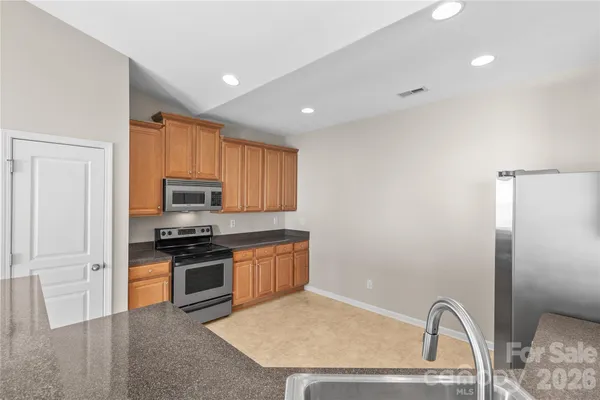 a view of an empty room with a window and kitchen view