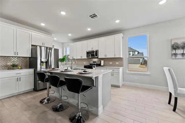 a kitchen with kitchen island a dining table cabinets and appliances