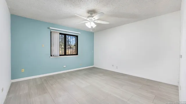 an empty room with a chandelier fan and windows