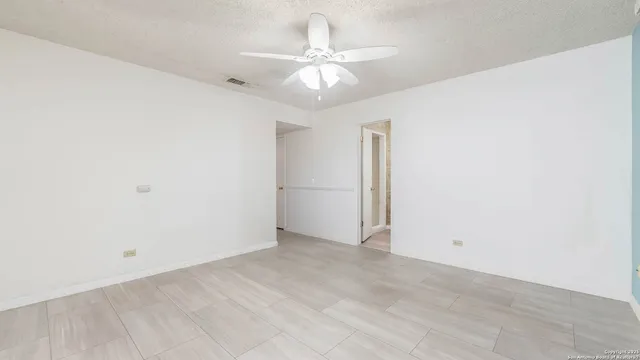 an empty room with a ceiling fan and a window