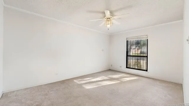 an empty room with windows and chandelier fan