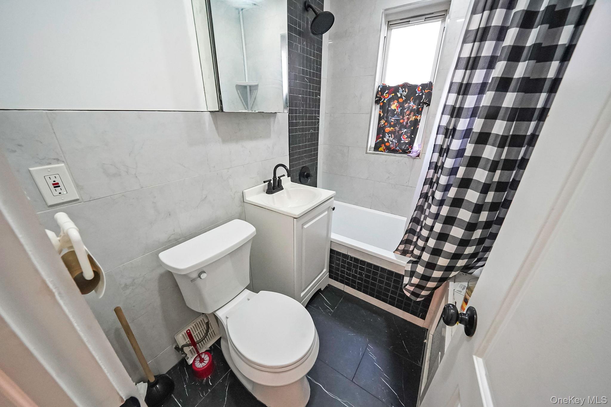 202-02 109th Avenue Queens, NY 11412 - Photo 22 of 26 Bathroom featuring tiled shower / bath, tile walls, vanity, and dark tile patterned flooring