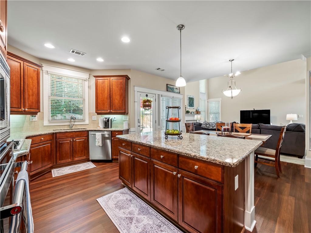 453 Hunter Street Northwest Norcross, GA 30071 - Photo 4 of 36 a kitchen with stainless steel appliances granite countertop wooden floors wooden cabinets a stove and a center island