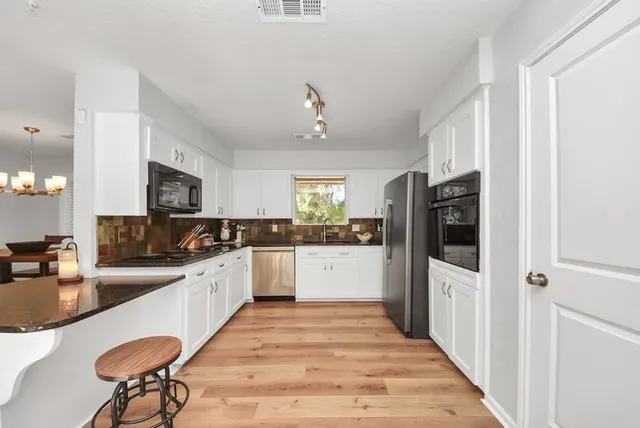 a large kitchen with kitchen island a dining table chairs stainless steel appliances and cabinets