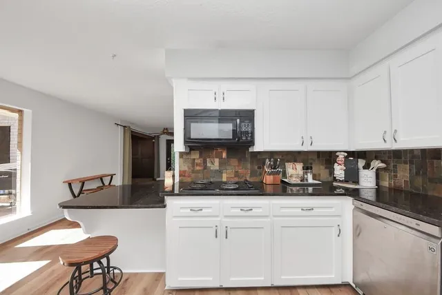 a kitchen with stainless steel appliances granite countertop a stove a sink and a white cabinets