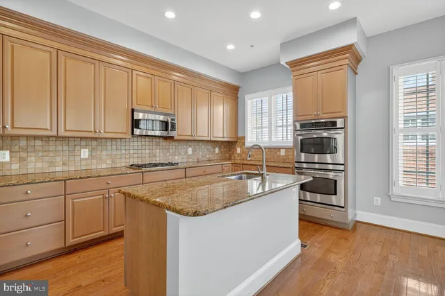 a kitchen with stainless steel appliances granite countertop a stove a sink and a microwave