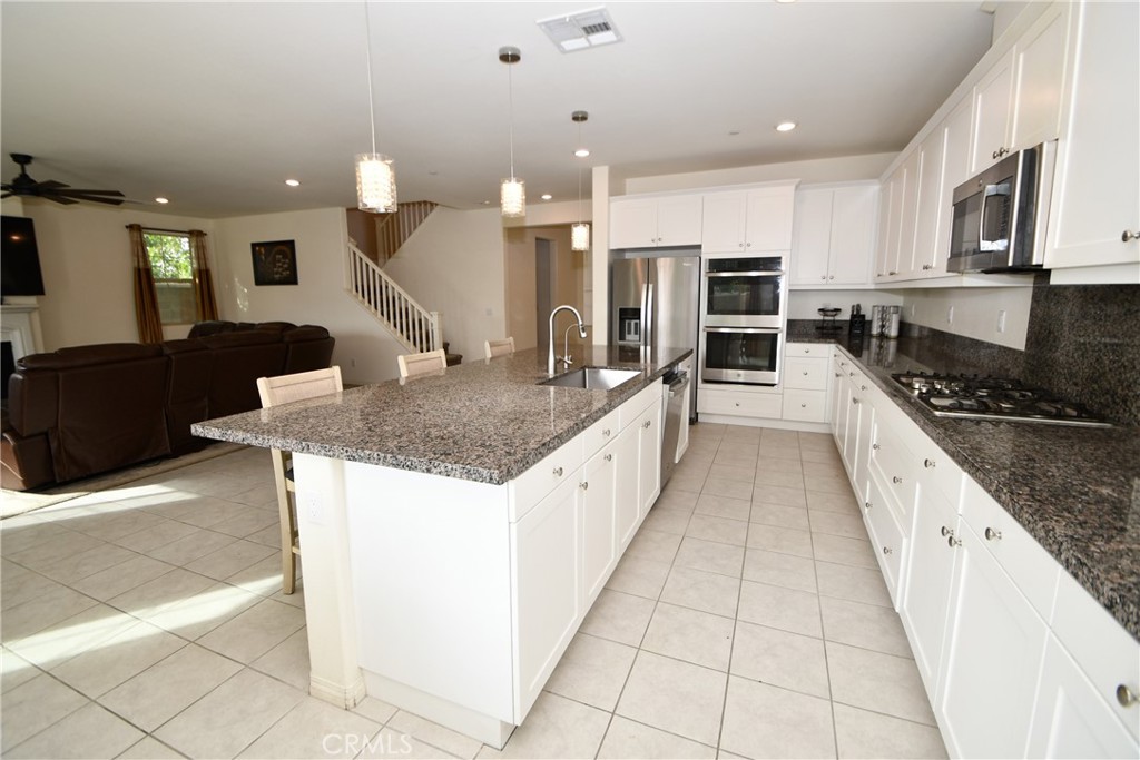 5367 Heitz Way Fontana, CA 92336 - Photo 14 of 50 a large kitchen with stainless steel appliances kitchen island granite countertop a large counter top and oven