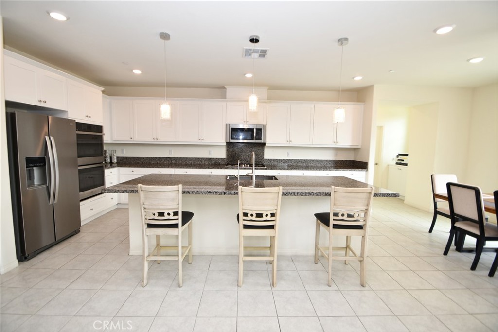 5367 Heitz Way Fontana, CA 92336 - Photo 15 of 50 a kitchen with stainless steel appliances kitchen island granite countertop a table and chairs in it