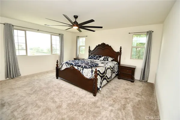 a bed sitting in a bedroom next to a window with a chandelier and dresser