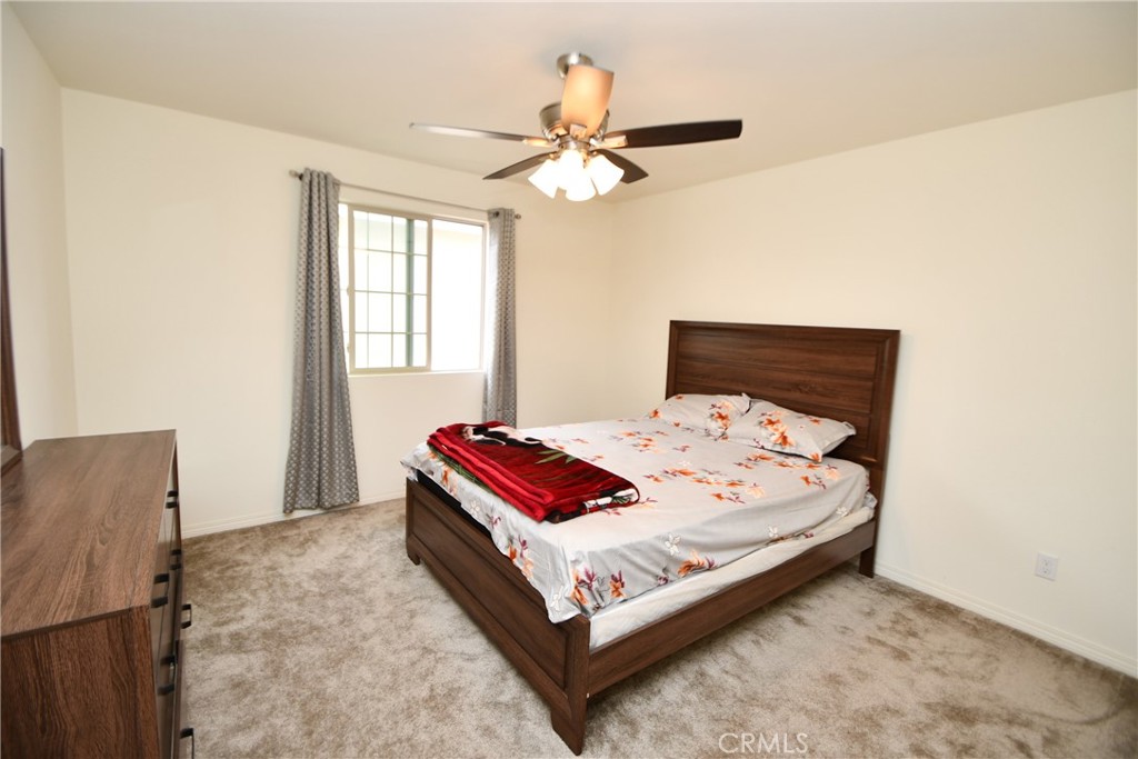 5367 Heitz Way Fontana, CA 92336 - Photo 27 of 50 a bed sitting in a bedroom next to a window with a chandelier and dresser