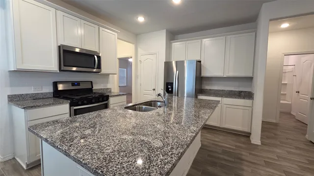 a kitchen with stainless steel appliances kitchen island granite countertop a stove refrigerator and microwave