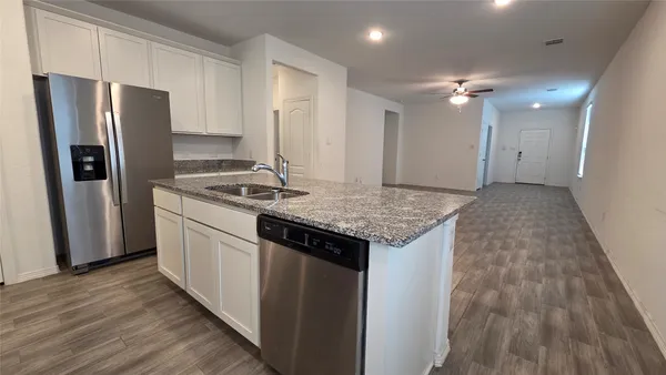 a kitchen that has a sink a refrigerator and wooden floor