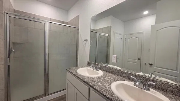 a bathroom with a granite countertop sink a mirror and a shower