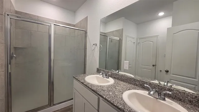 a bathroom with a granite countertop sink a mirror and a shower
