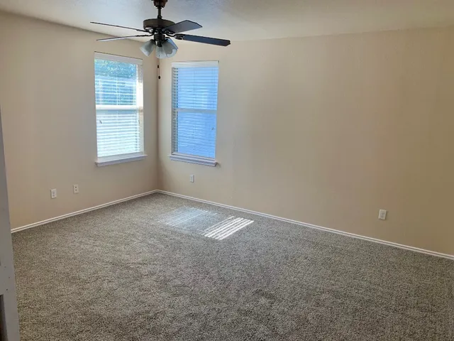 an empty room with windows and fan