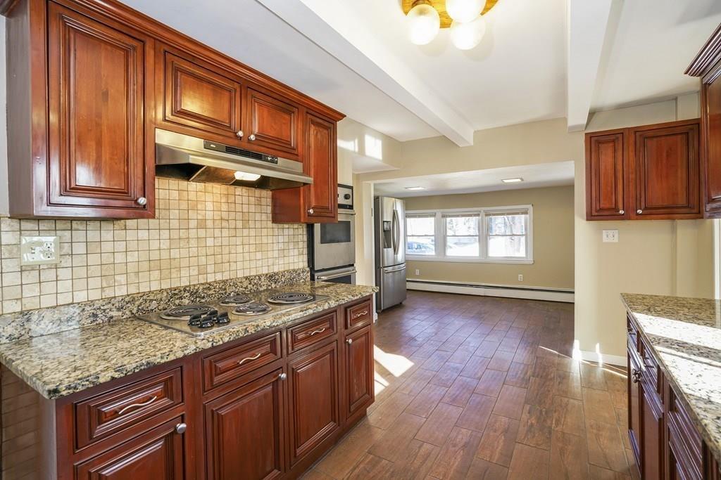 1309 Washington Street Canton, MA 02021 - Photo 6 of 35 a kitchen with stainless steel appliances granite countertop wooden floors and wooden cabinets