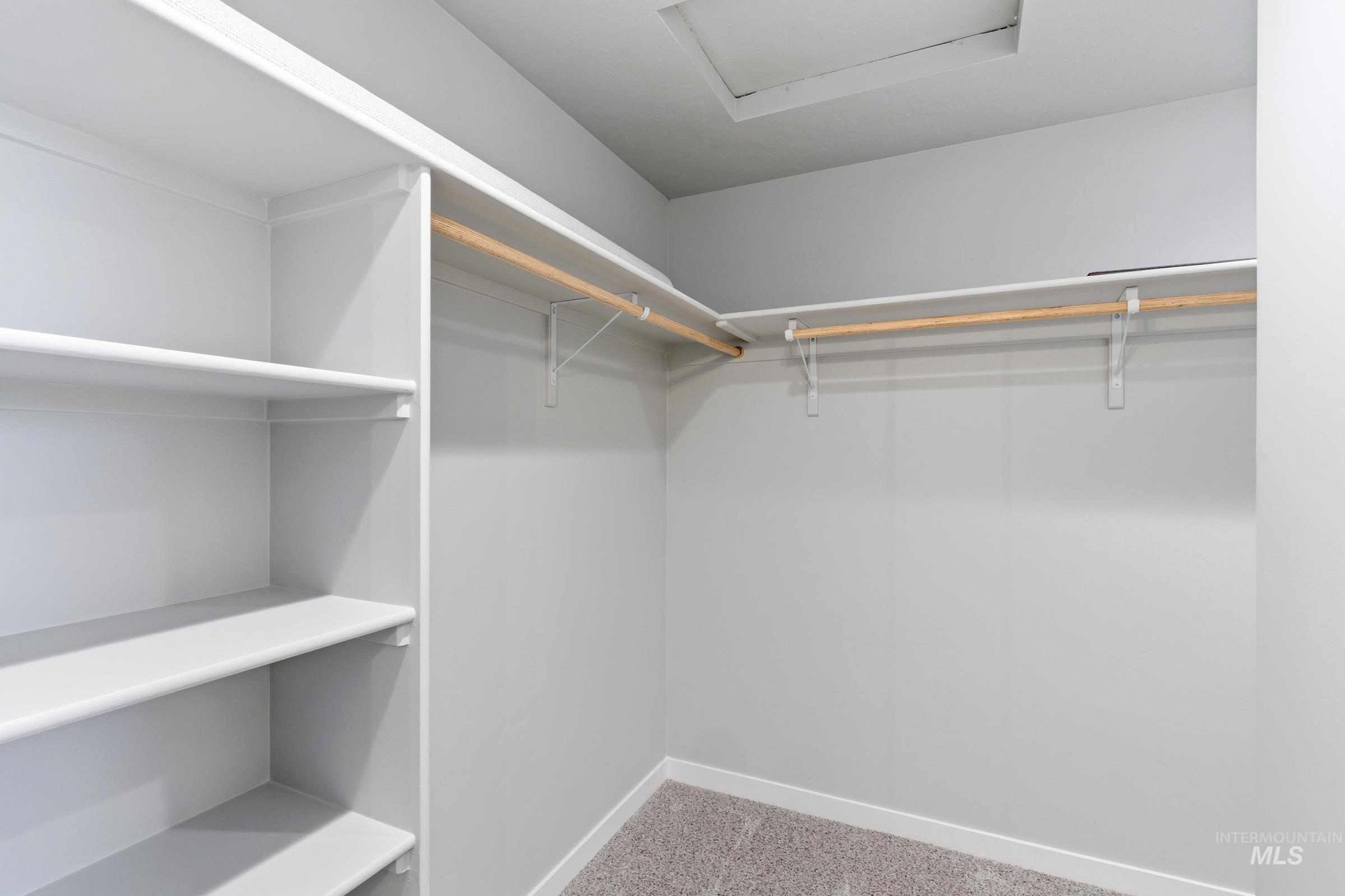 2374 West Fallon Loop Nampa, ID 83651 - Photo 22 of 24 Walk-in closet featuring built-in shelving, two clothing rods, light gray walls, and carpet flooring