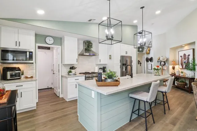 a open kitchen view with stainless steel appliances granite countertop a stove a refrigerator a oven a dining table and chairs with wooden floor