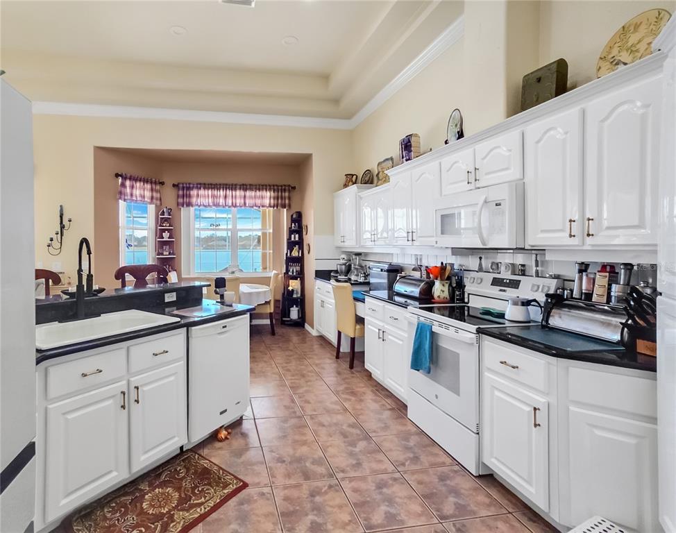 77 Hickory Loop Ocala, FL 34472 - Photo 13 of 50 a kitchen with kitchen island granite countertop lots of white cabinets and white appliances