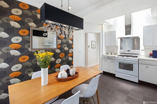 a kitchen with stainless steel appliances a sink a stove a chimney a dining table and chairs