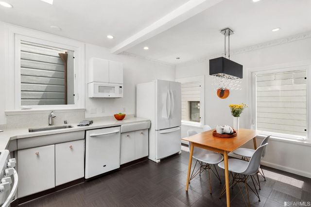 a kitchen with stainless steel appliances a white table chairs and a refrigerator
