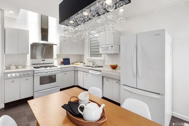 a kitchen with stainless steel appliances a white refrigerator a sink a stove a dining table and chairs