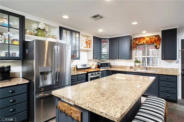 a kitchen with stainless steel appliances granite countertop a refrigerator a sink and a stove