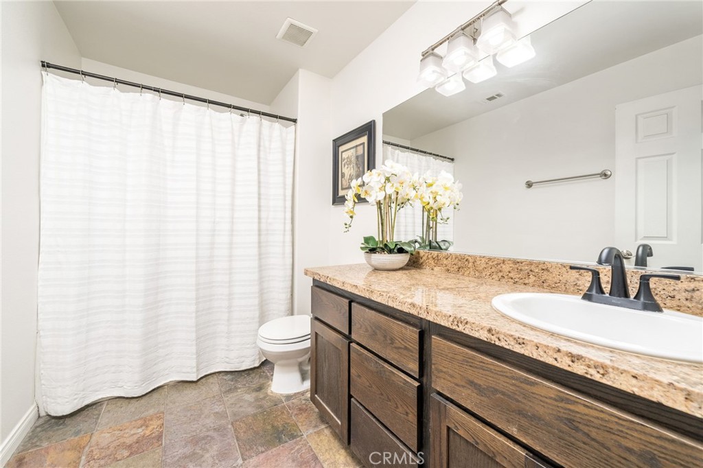7575 Rancho Road Pinon Hills, CA 92397 - Photo 24 of 38 a bathroom with a granite countertop sink a toilet and a mirror