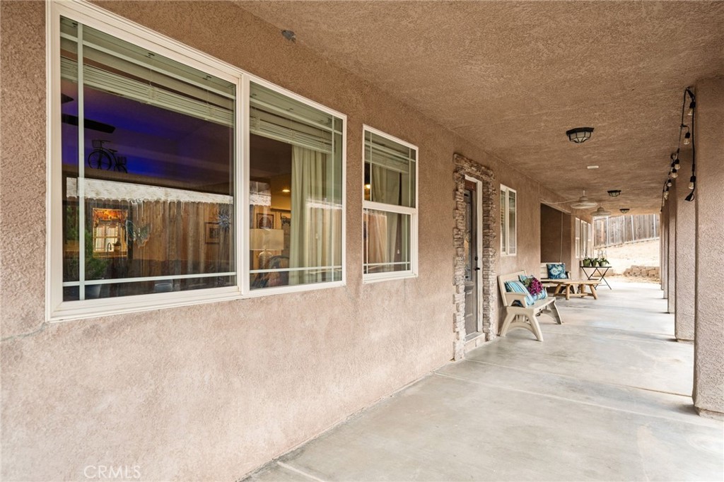 7575 Rancho Road Pinon Hills, CA 92397 - Photo 29 of 38 a view of a porch with a table and chairs and floor to ceiling window