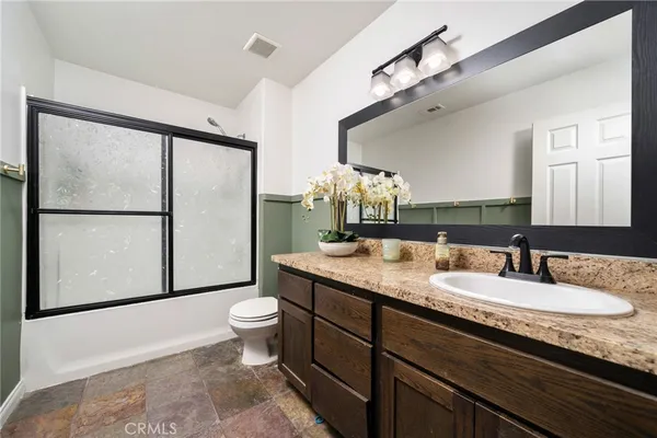 a bathroom with a granite countertop sink toilet and mirror