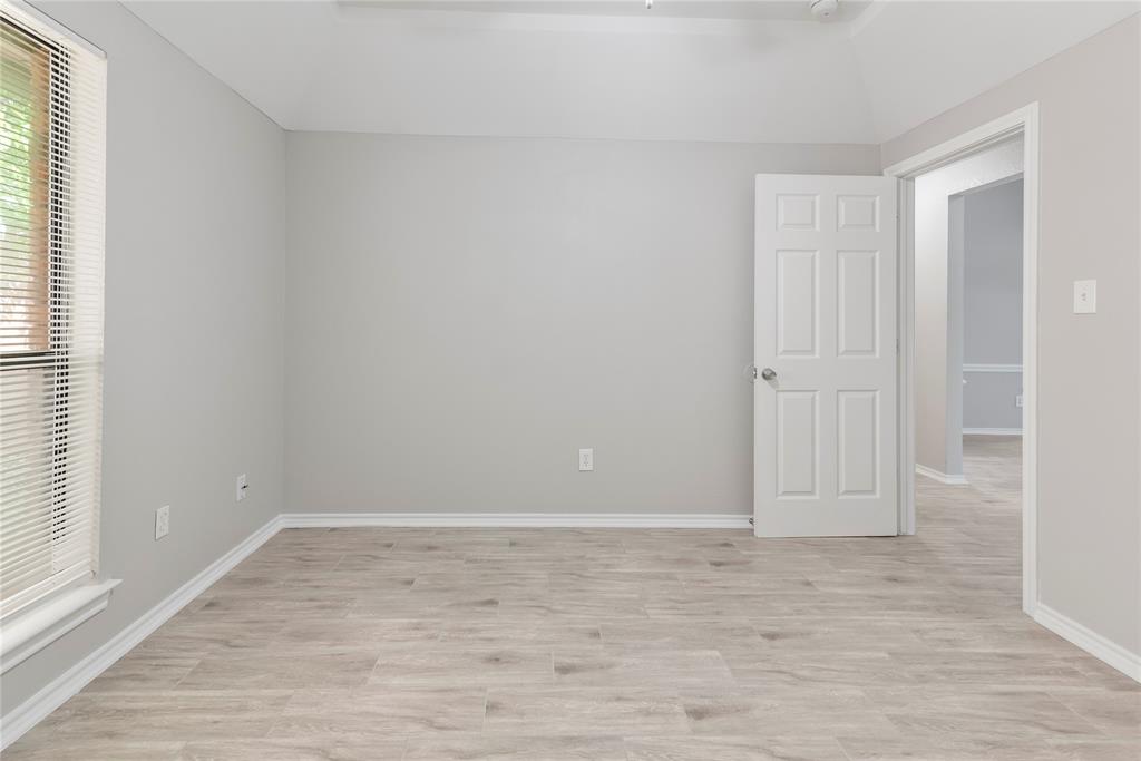 304 Moore Creek Road, Unit 300 Hurst, TX 76053 - Photo 8 of 17 Spacious interior room featuring wood-finish flooring, a vaulted ceiling, and neutral gray walls