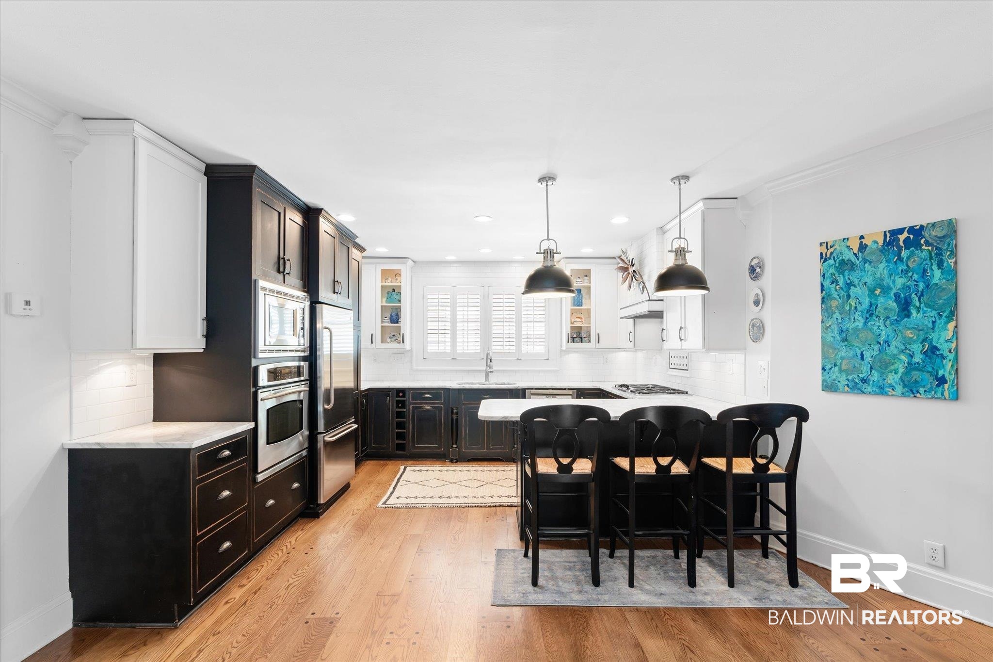 202 Woodlands Avenue Mobile, AL 36607 - Photo 10 of 53 Kitchen featuring tasteful backsplash, a breakfast bar area, hanging light fixtures, stainless steel appliances, and light hardwood / wood-style flooring