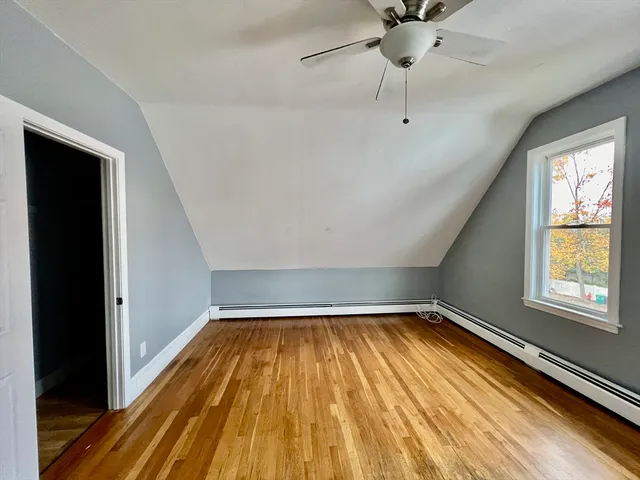 a view of a room with wooden floor fan and windows