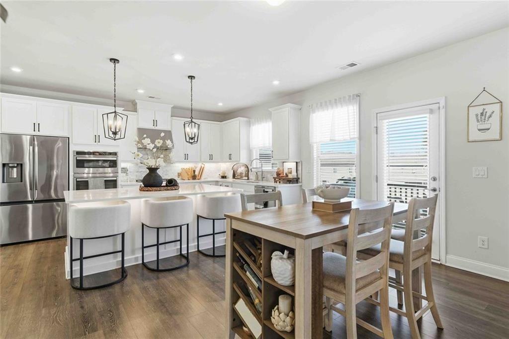 4631 Leader Lane Duluth, GA 30096 - Photo 17 of 55 a kitchen with stainless steel appliances a white table chairs and a wooden floor