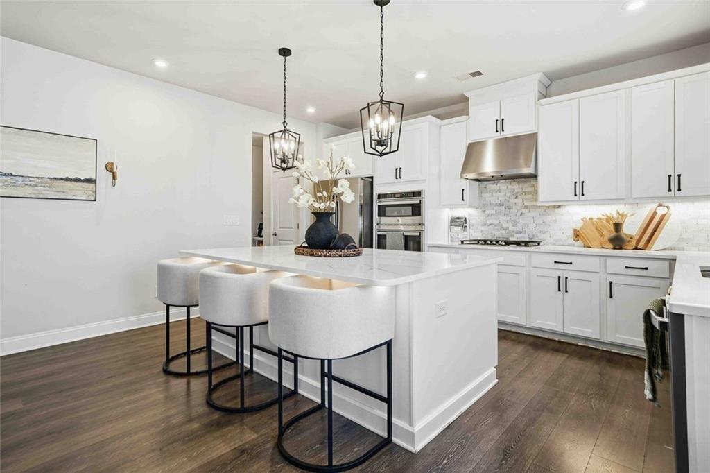 4631 Leader Lane Duluth, GA 30096 - Photo 22 of 55 a kitchen with stainless steel appliances granite countertop a sink a stove a refrigerator and chairs with wooden floor