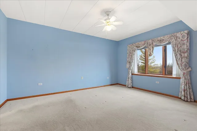an empty room with windows and chandelier fan
