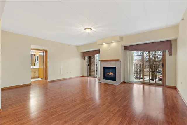 an empty room with wooden floor fireplace and windows