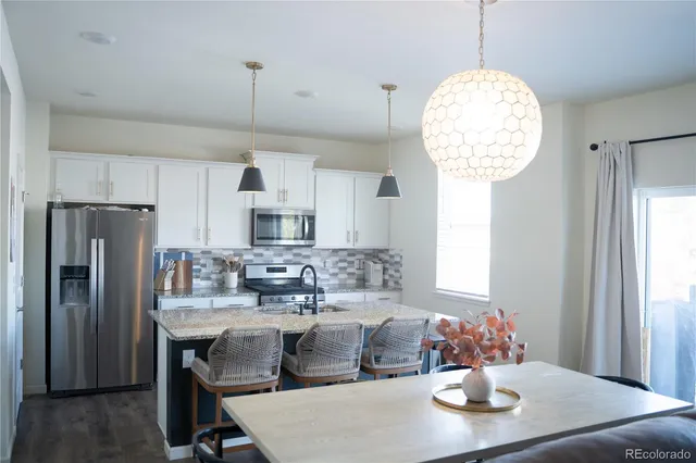 a kitchen with stainless steel appliances chandelier dining table and chairs