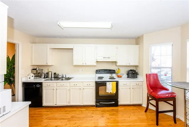 a kitchen with a stove a sink and white cabinets