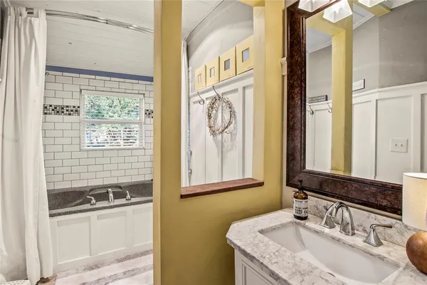 a bathroom with a granite countertop sink a mirror and a shower