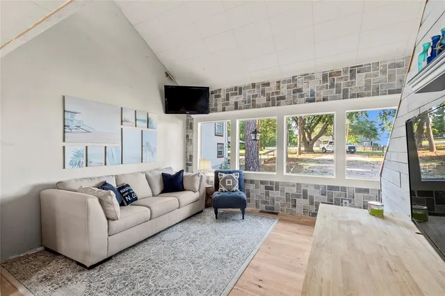 a living room with furniture a flat screen tv and a floor to ceiling window