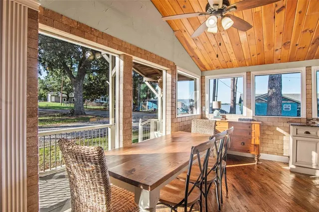 a dining room with wooden floor a chandelier a glass table and chairs