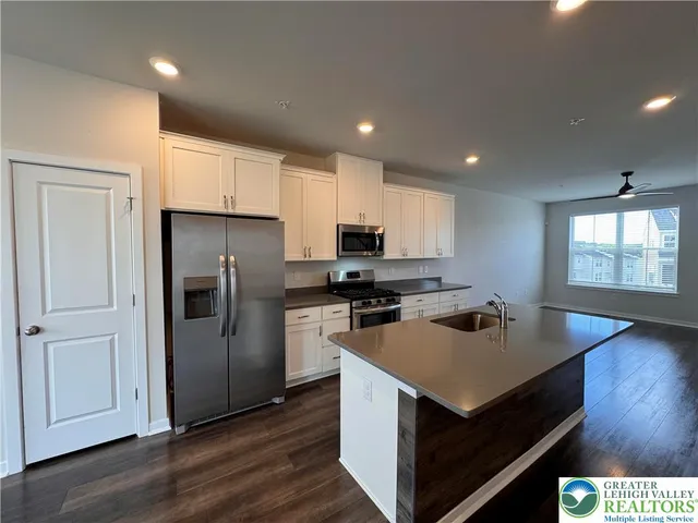 a kitchen with a refrigerator a sink dishwasher and a stove with wooden floor