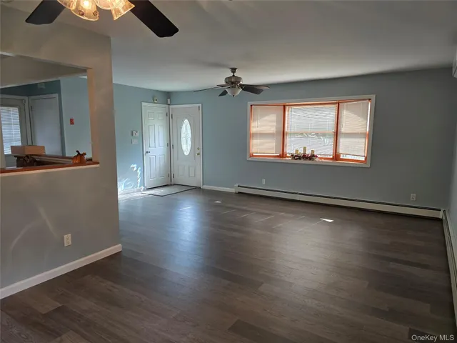an empty room with wooden floor chandelier fan and windows