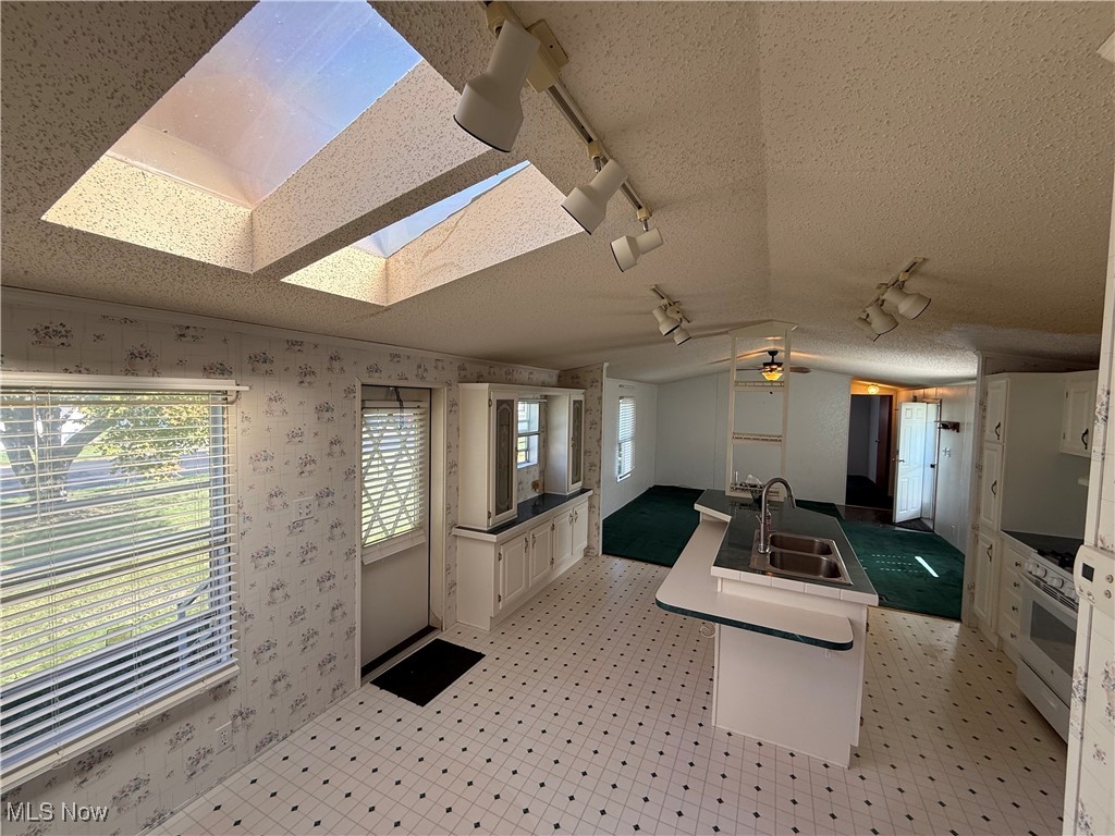 18592 Edwards Road, Unit 137 Doylestown, OH 44230 - Photo 7 of 17 Kitchen featuring rail lighting, a center island with sink, white cabinetry, gas range gas stove, and a textured ceiling